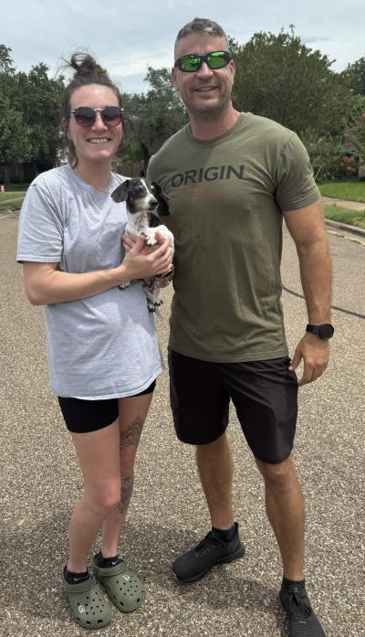 Two people holding the senior dog Weiner