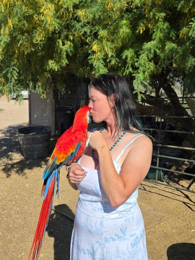 Mary holding and kissing Beau the parrot
