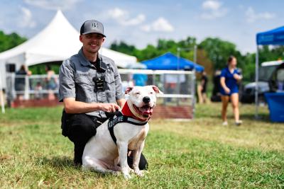 Person with a large white dog in front of some tents at the Best Friends Super Adoption in Northwest Arkansas