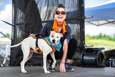 Laughing person on a stage with a dog at the Best Friends Super Adoption in Northwest Arkansas
