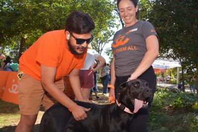 Two smiling people standing with a dog at a community event