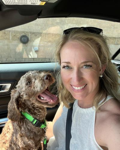 Smiling person sitting in a vehicle with Bailey the dog in her lap