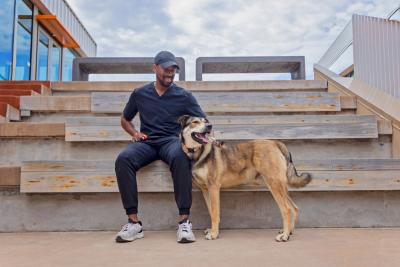 Person sitting outside on some stairs next to a dog