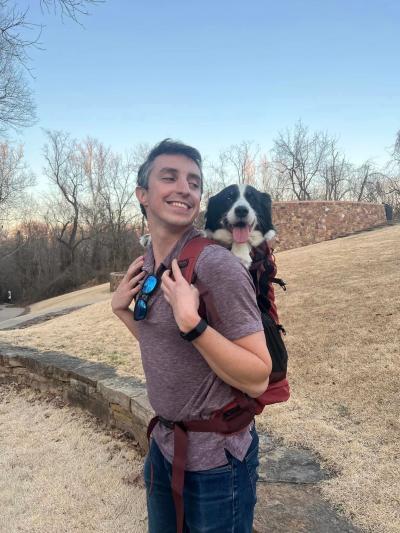 Ducky the dog in a backpack on Alex's shoulders