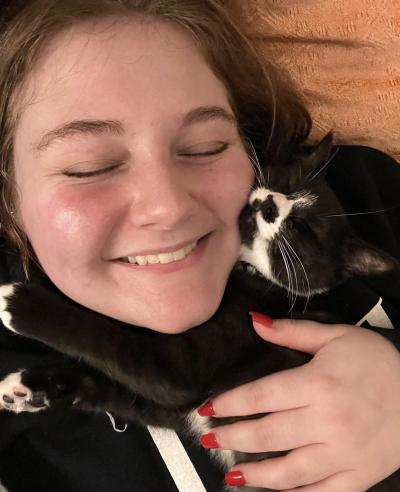 Smiling person lying down and snuggling with Charlie the black and white cat
