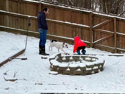 Neo the dog playing in the snow in a yard with two people