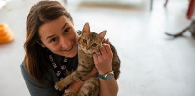 Woman in dark shirt holding tabby cat
