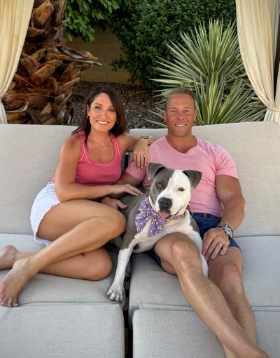 Pearl the dog with Jess and her husband sitting together on an outdoor couch