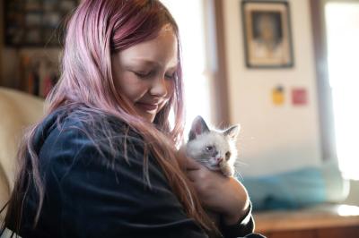 Smiling person holding a small kitten