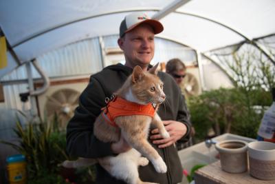 Best Friends employee holding Pumpkin the cat in the greenhouse