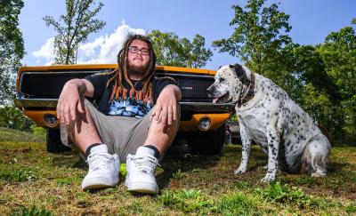 Braxton Louch sitting in front of a vehicle with a dog