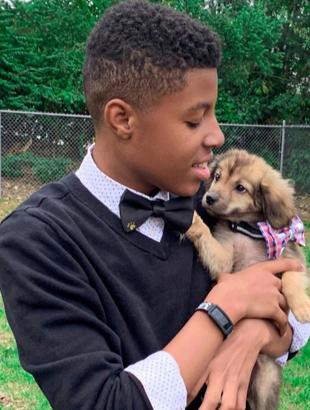 Sir Darius Brown holding a puppy who is wearing one of his handmade bow ties