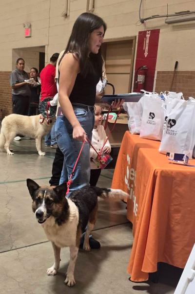 Person with a dog on a leash in front of the Best Friends table