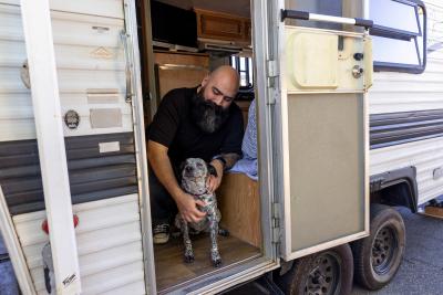 Chris Alton and a foster dog at the open side door of the RV