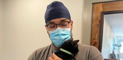 Volunteer Ramandeep Singh wearing a mask and holding a black cat