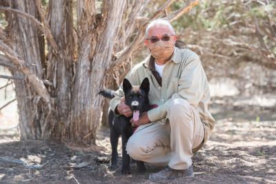 Keith Slim-Tolagai under a tree with a black dog