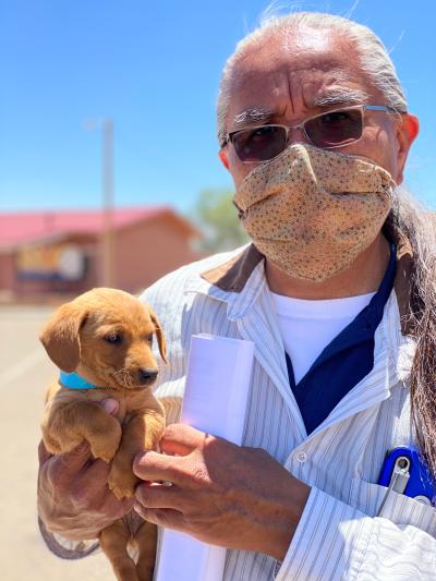 Keith Slim-Tolagai wearing a mask and holding a puppy