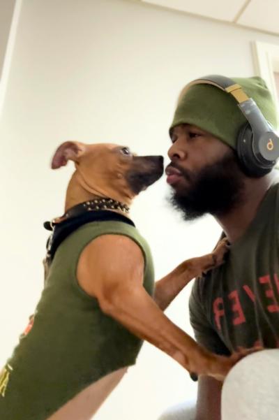 Pudding the dog nose-to-nose with her adopter, who is wearing a hat and headphones