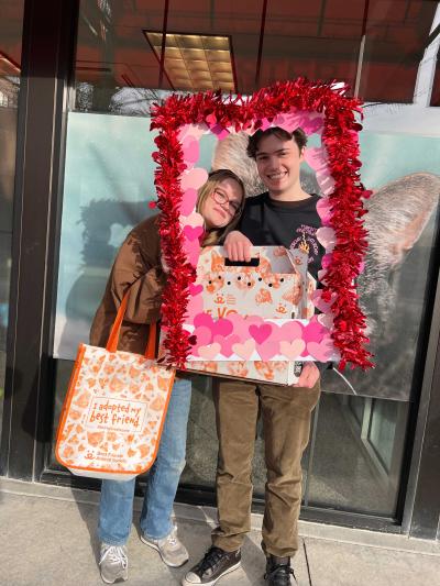 A couple with a newly adopted cat in a carrier in a Valentine's Day frame