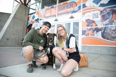 Two people kneeling with a dog between them at the Best Friends Super Adoption in Utah