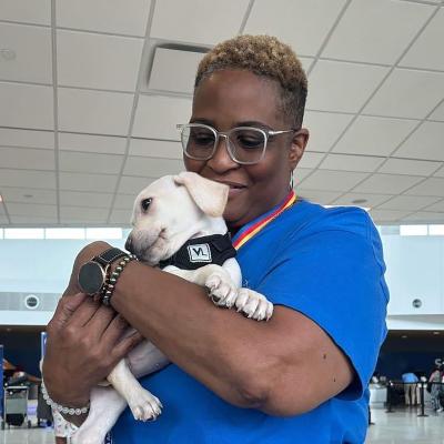 Volunteer for Southwest Animal Transport Team (SWATT) holding a white puppy