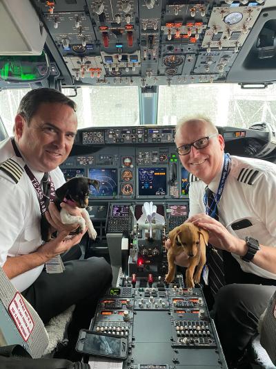 Two Southwest Animal Transport Team (SWATT) pilots in the cockpit holding puppies
