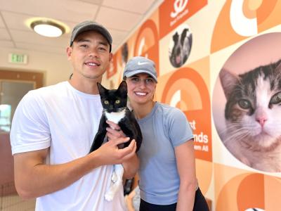 Sam Junqua and Emma Besier holding a black and white cat