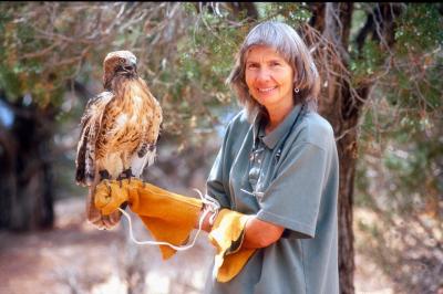 Vintage photo of Sharon St. Joan beside a tree holding a bird of prey on a gloved hand