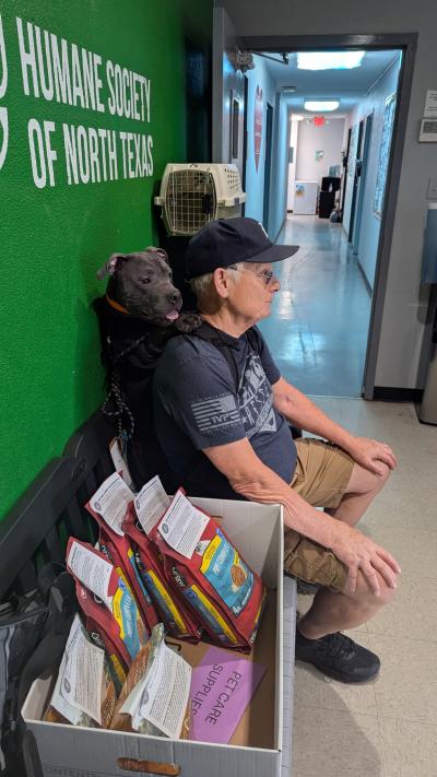 Man sitting on bench at shelter with Gabriel the dog in a backpack on his back