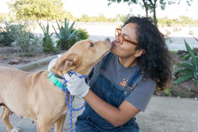 Brown dog kissing the face of a person wearing a Best Friends T-shirt