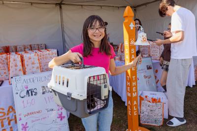 Person holding a cat carrier in a booth containing adoption bags at the Best Friends Super Adoption in Los Angeles