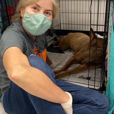 Volunteer Penny Burleson next to a dog in a wire kennel
