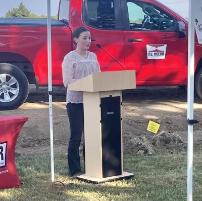 Libby Aeschleman behind a podium with a red truck in the background