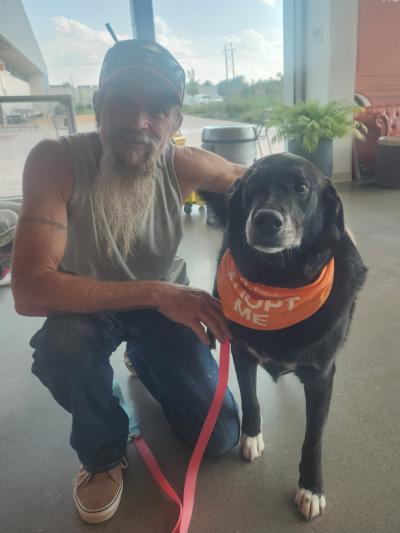 Thelma the dog wearing a bandanna next to the person adopting her