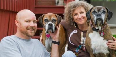 Man and woman in sitting on porch with two boxers