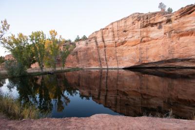 The area of Three Lakes in Kanab, Utah, featuring a body of water, trees, and a red rock cliff