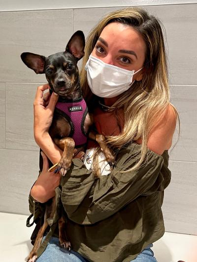 Tres the dog being held by her adopter, who is masked