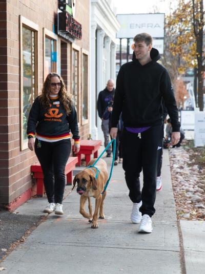 Kyle Filipowski walking Topino the dog beside a person wearing a Best Friends sweatshirt