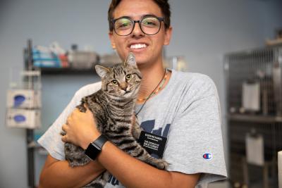 Volunteer Ben Richards holding a brown tabby cat in his arms