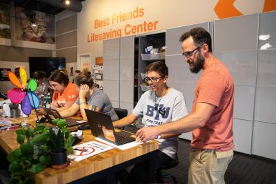 Volunteer Ben Richards working on a laptop with another person at the Best Friends Lifesaving Center