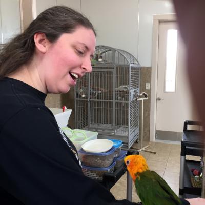 Elizabeth Duszak smiling at a yellow and green parrot