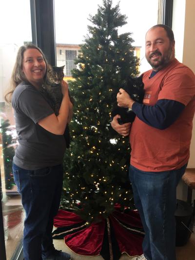 Russ and Elizabeth Duszak holding Snow White and Macchiato the cats in front of a Christmas tree