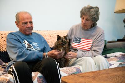 Brenda and Marty Winnick sitting on a couch with a tortoiseshell cat between them