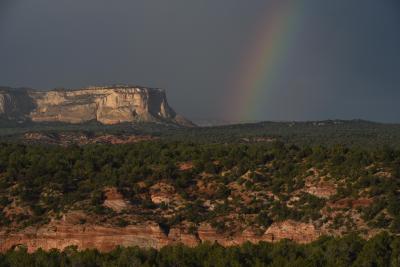 Rainbow beside a white cliff with a dark gray sky