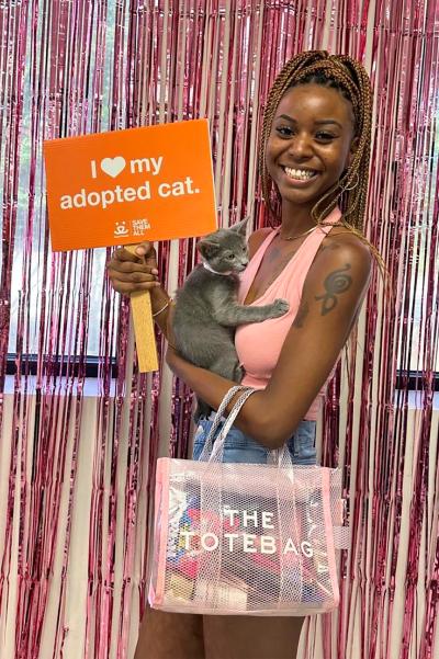 Ivory smiling and holding Nermal the kitten and a sign that says, I heart my adopted cat