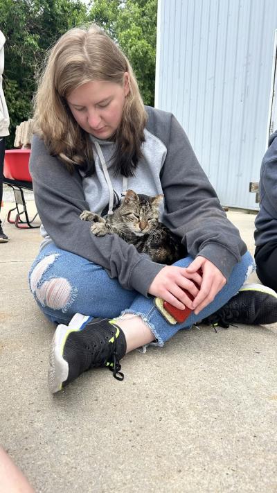 Animal Protective League staffer sitting on the ground with a cat in her lap