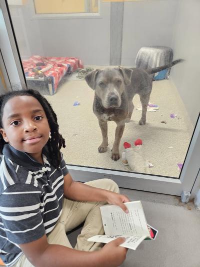 Nehemiah reading to a dog in a kennel
