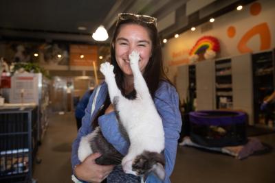 Prancer the cat being held upside down by a smiling person with her front paw on the person's face