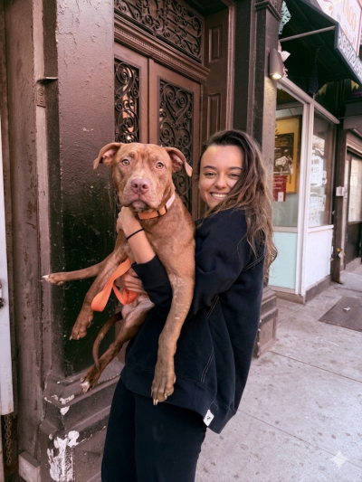 Masha holding Cinnamon the dog in front of a building