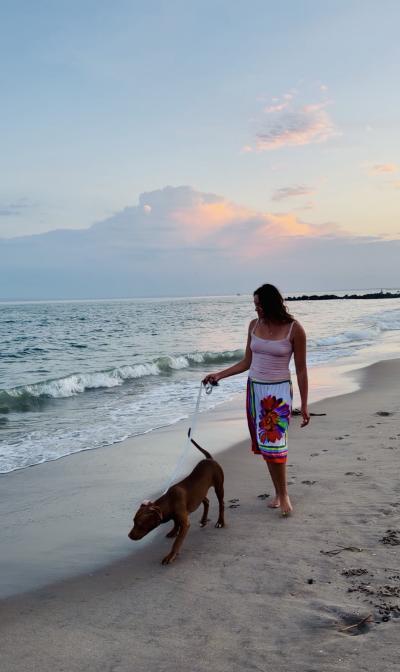 Masha and Cinnamon the dog walking at the beach during a sunset